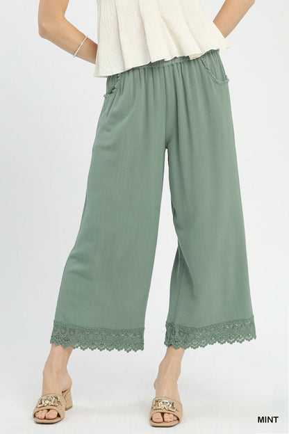 Front view of linen wide-leg pants with elastic waistband and lace trim, made from 55% linen and 45% cotton, relaxed fit.