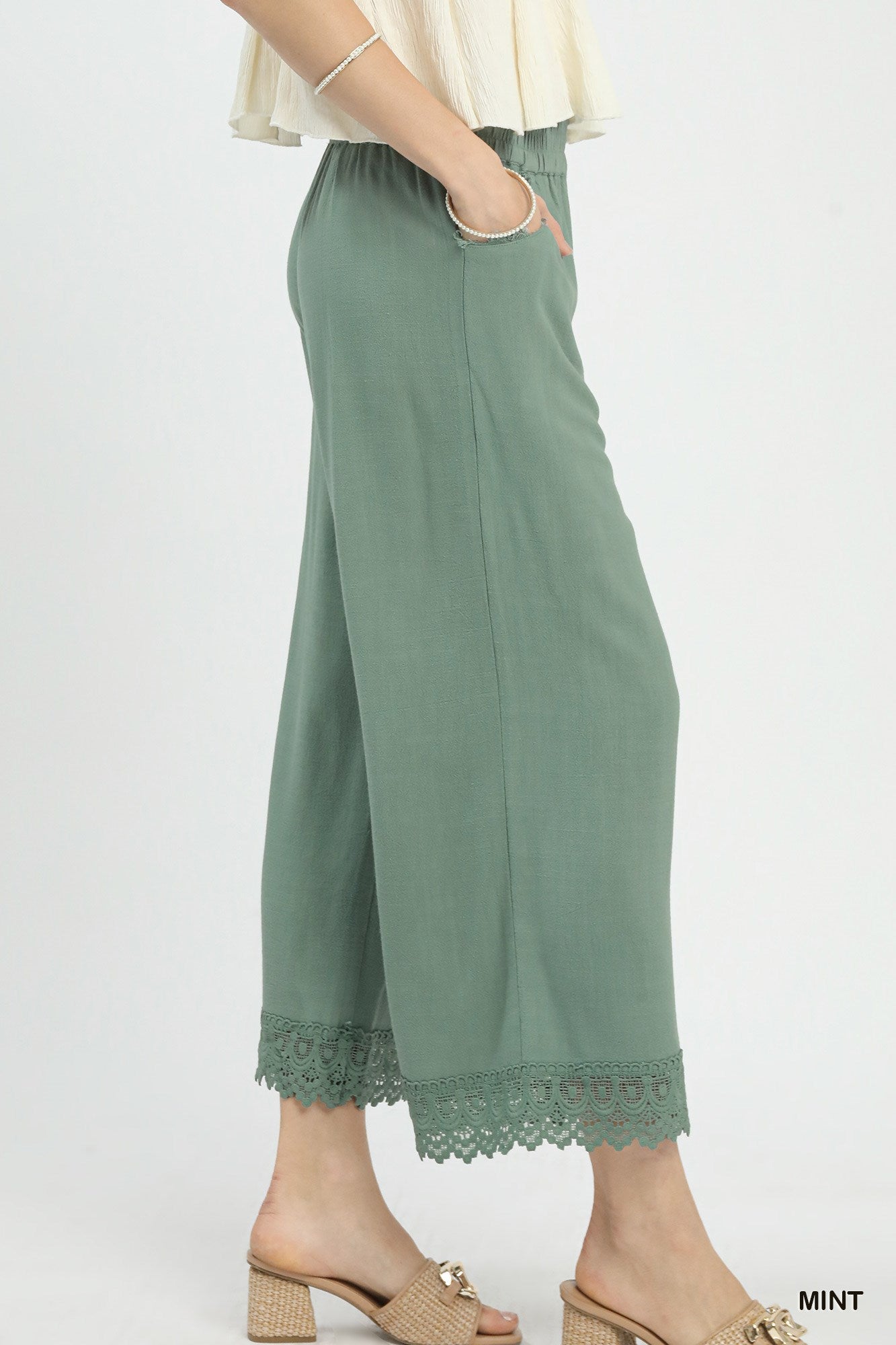Side view of linen wide-leg pants showing flowy silhouette and lace trim along the hem, lightweight breathable fabric.