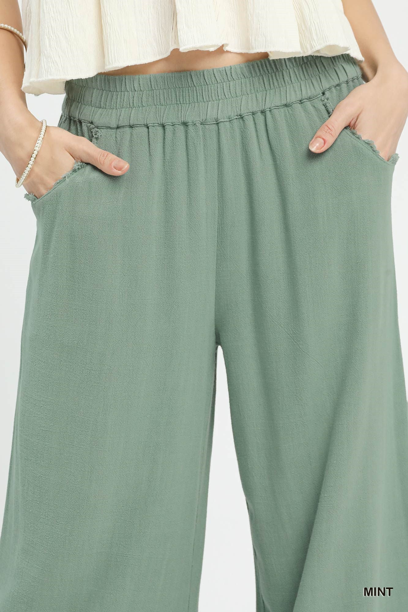 Close-up of lace trim on linen wide-leg pants, highlighting texture and delicate design, breathable linen-cotton fabric.