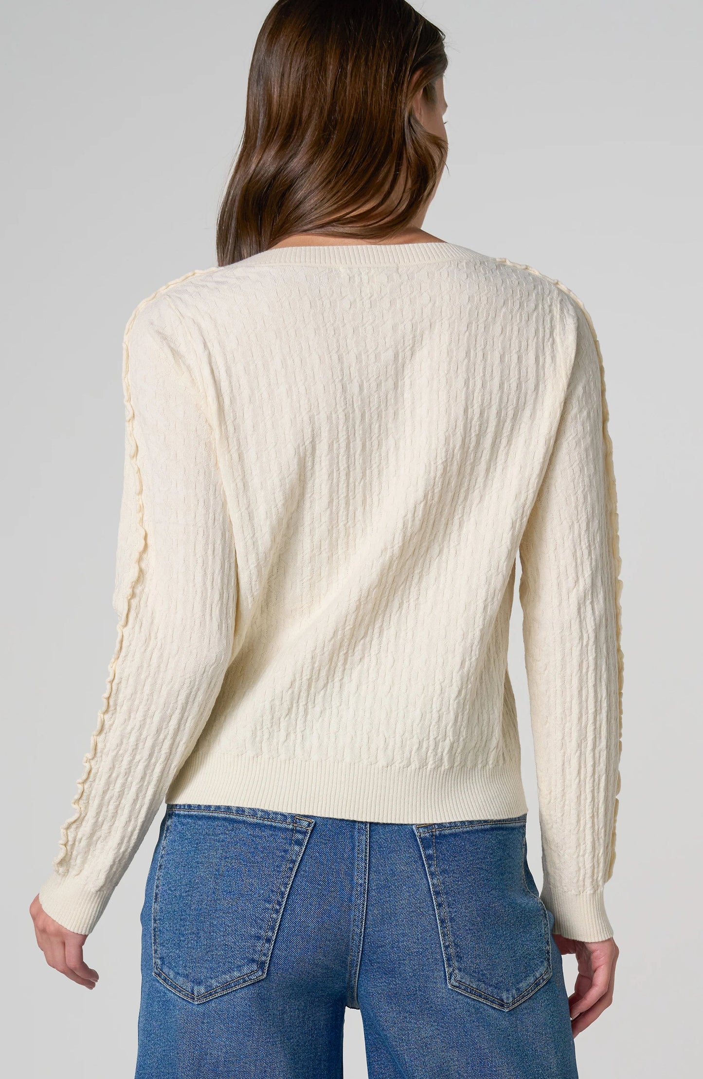 Back Soft knit women's button-front cardigan with long sleeves, delicate ruffle details, and ribbed neckline, hem, and cuffs.