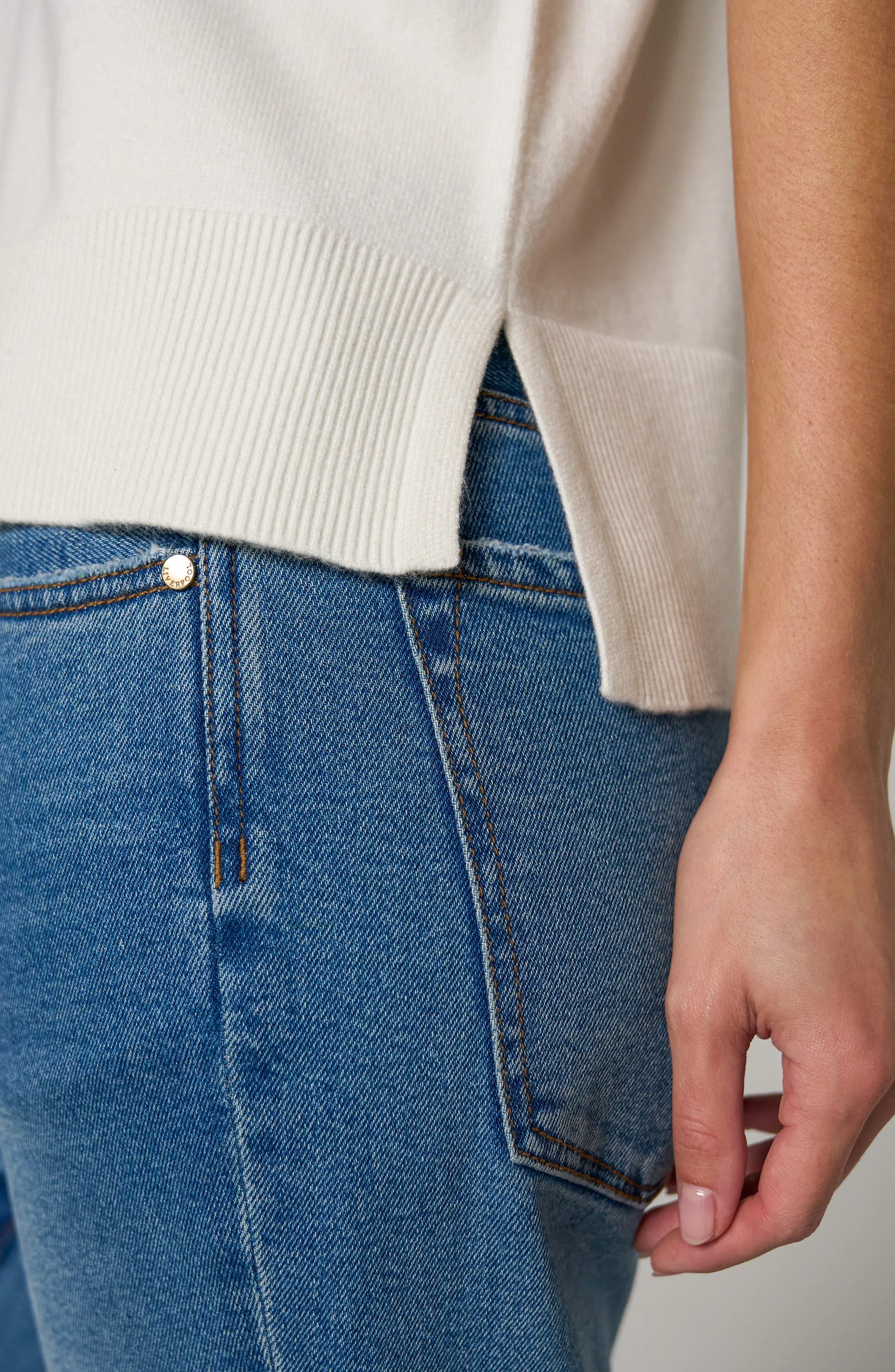 Detail Soft knit women's V-neck dolman sleeve sweater with relaxed fit, short sleeves, stepped hem, and ribbed hem.